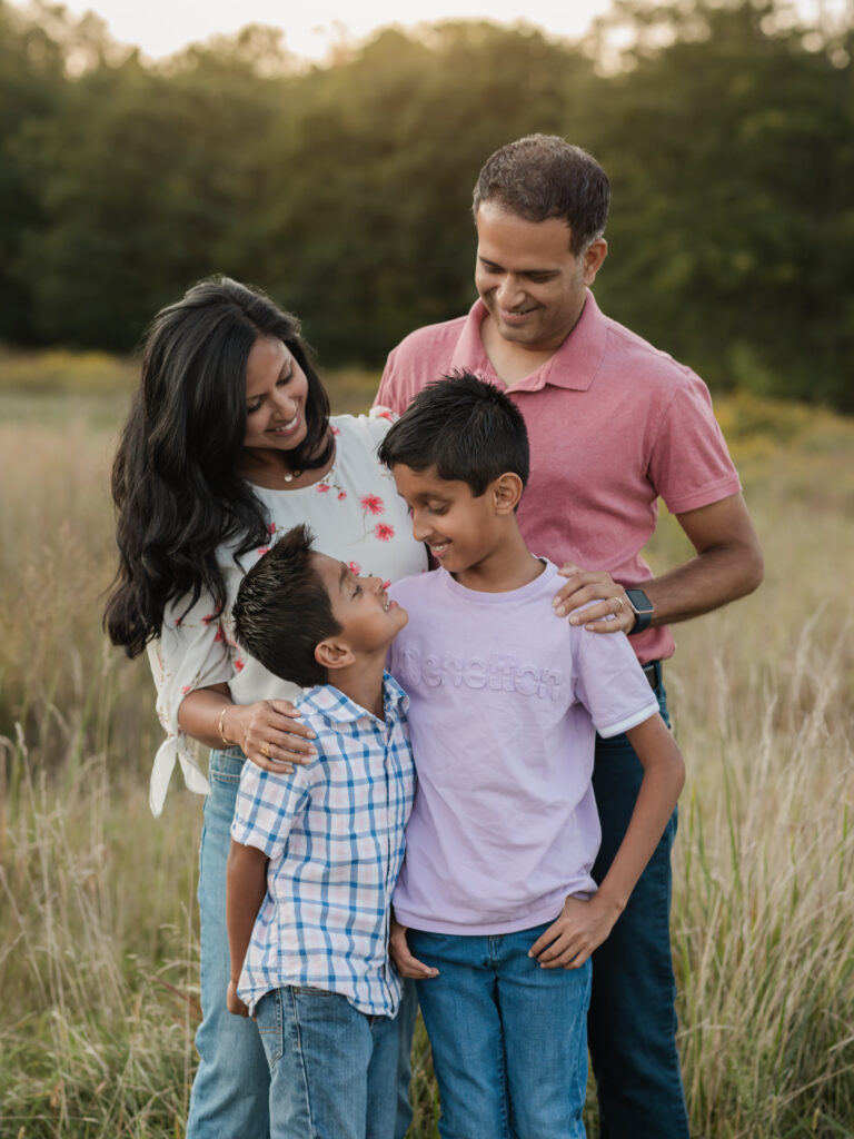 mom, dad and two sons posing in park for family photos 