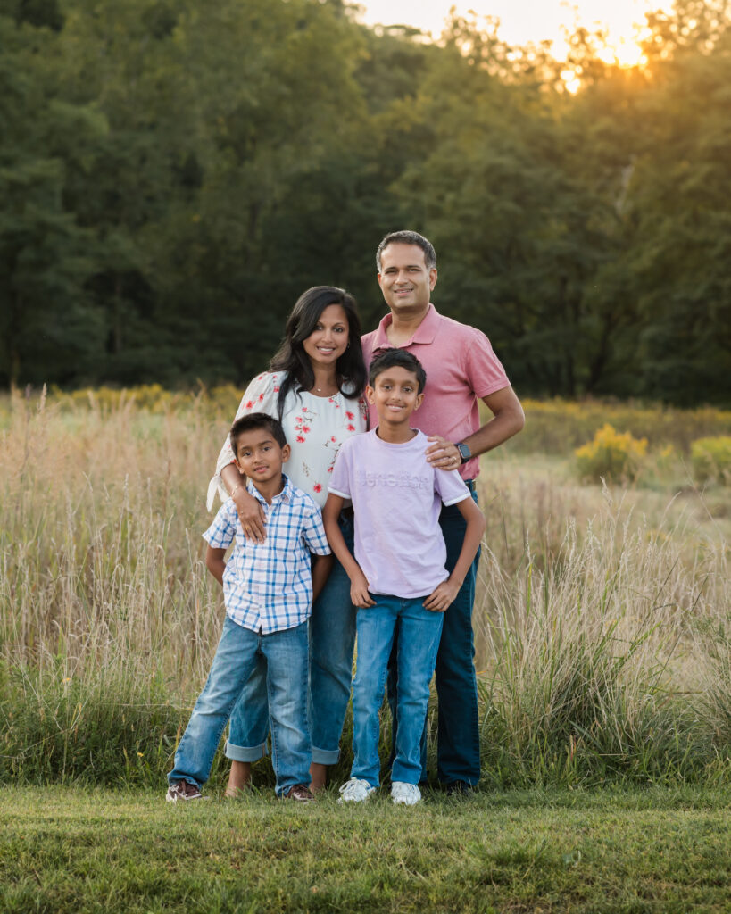 mom, dad and two sons posing in park for family photos 