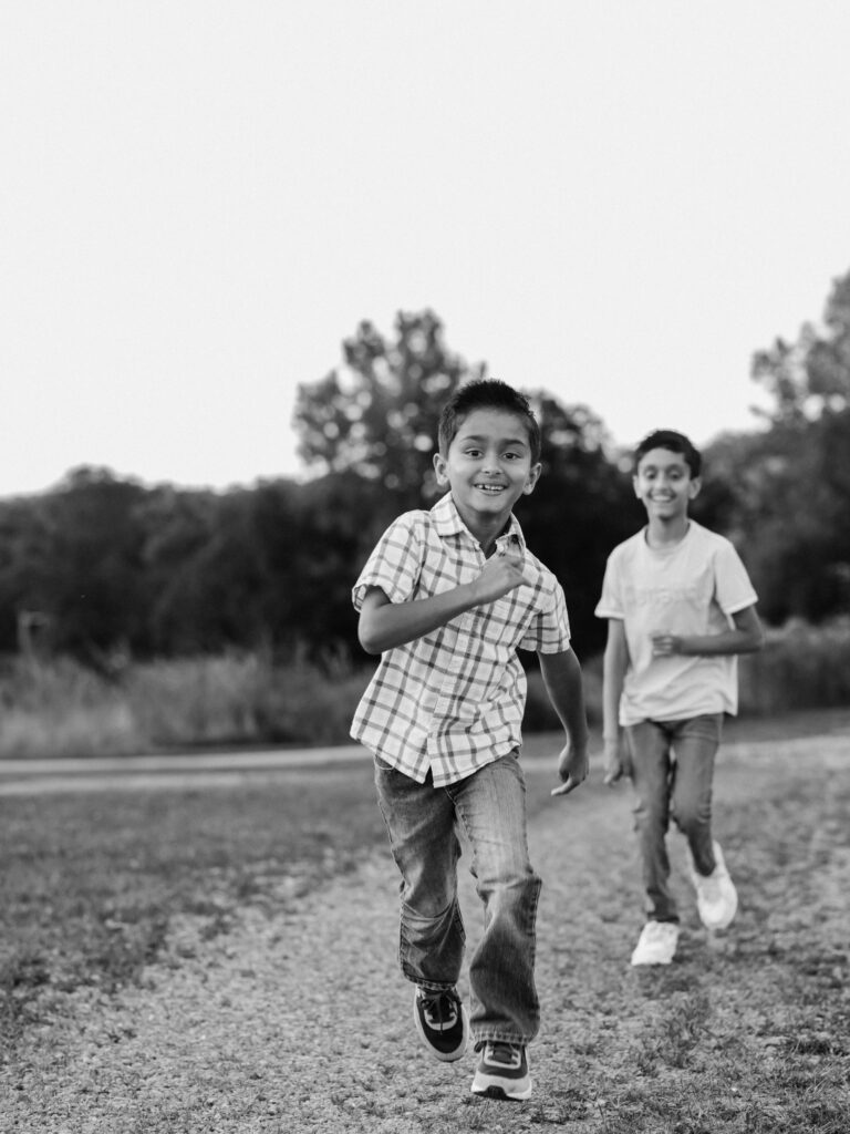 two brothers running in park for family photos 