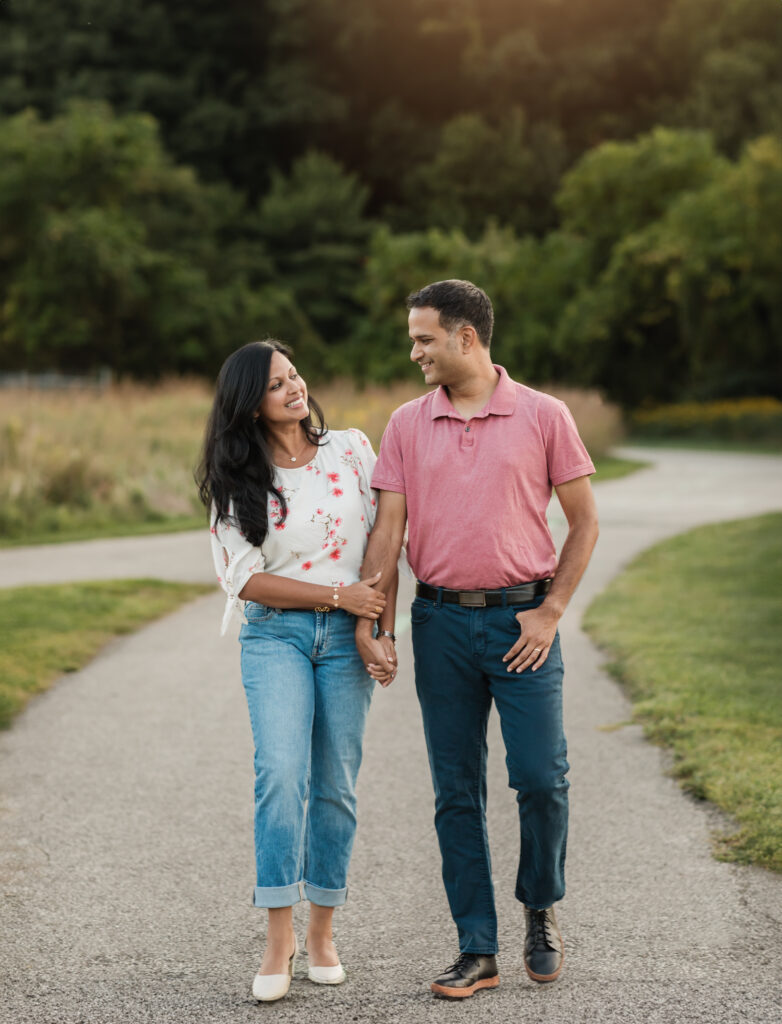 husband and wife holding hands walking in park for family photos Westcreek Reservation