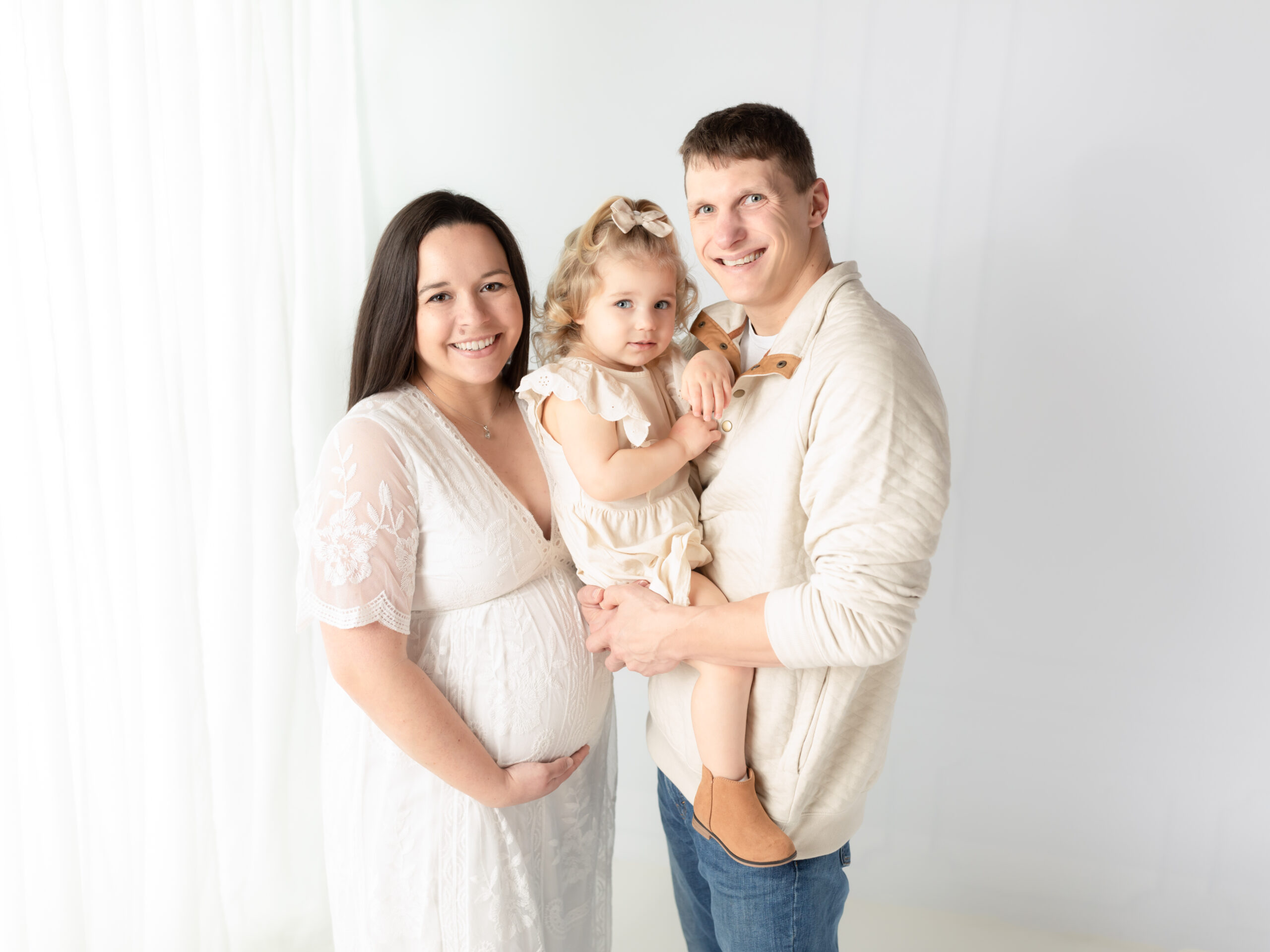 mother and father holding two year old daughter for maternity photoshoot The Womb Wellness Center