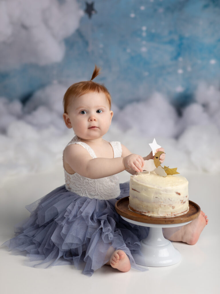 one year old girl eating cake for photoshoot