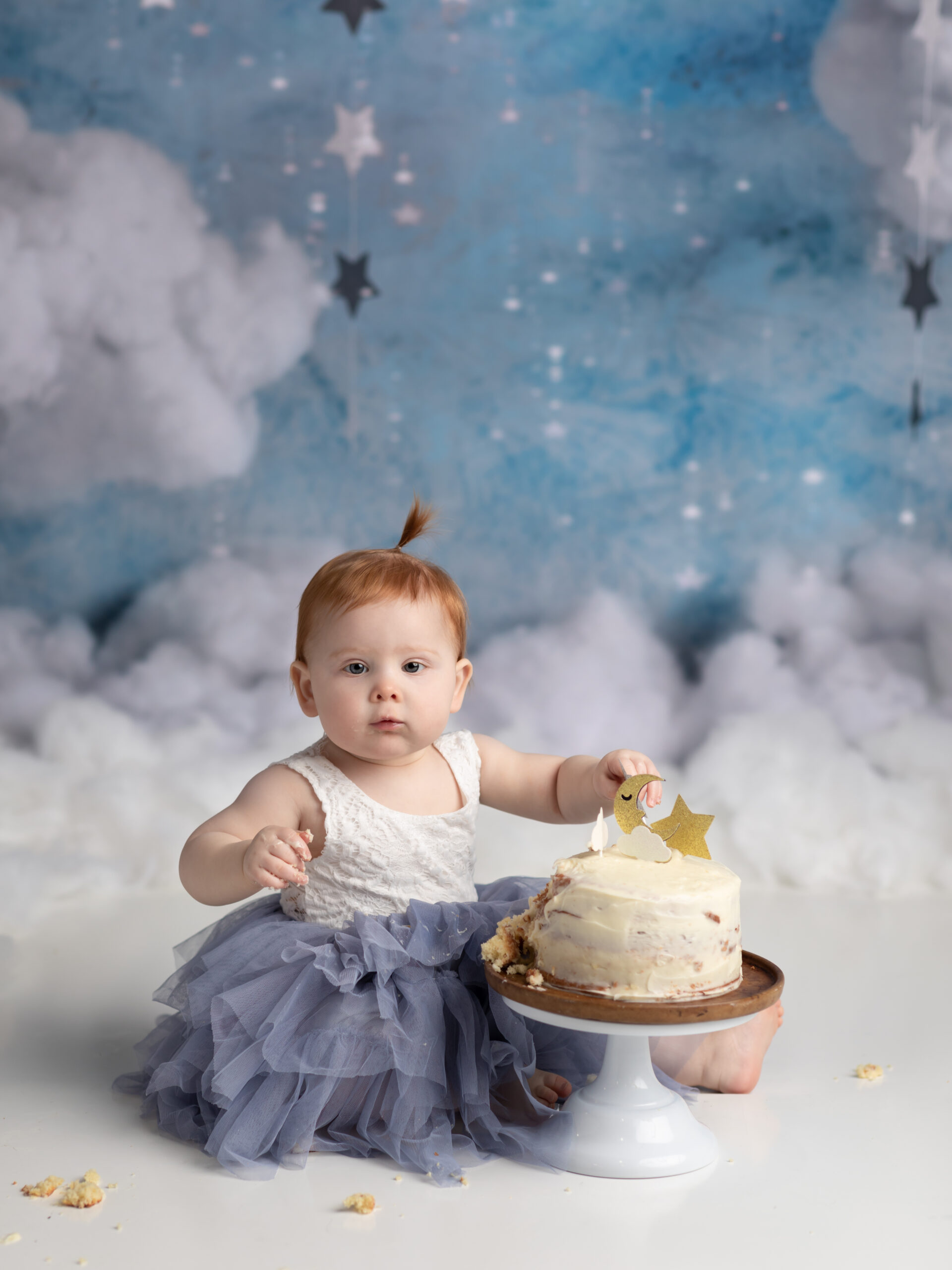 one year old girl eating cake for photoshoot