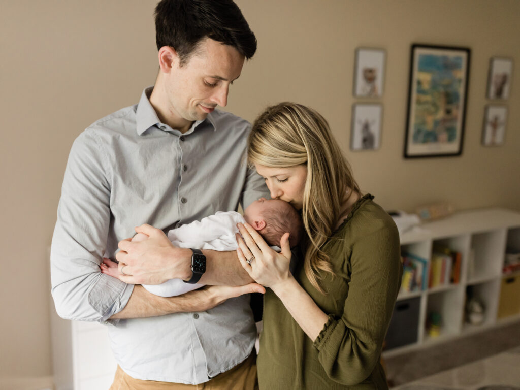 Mom and dad holding newborn baby boy in nursery for photos
