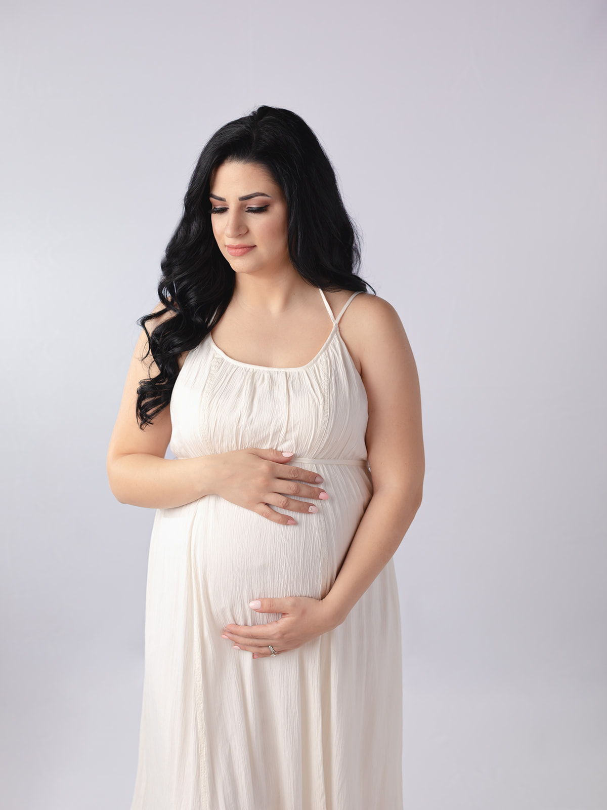 mom to be in white maternity gown cradling her bump in a studio prenatal yoga Cleveland