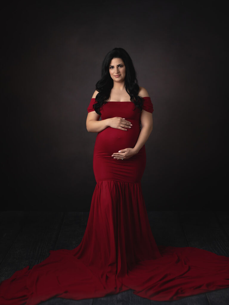 pregnant woman in maroon maternity gown in a studio