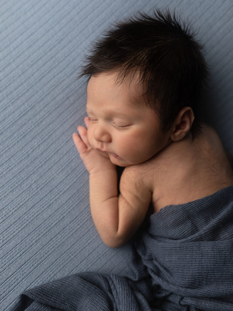 newborn baby boy sleeping on a blue blanket 