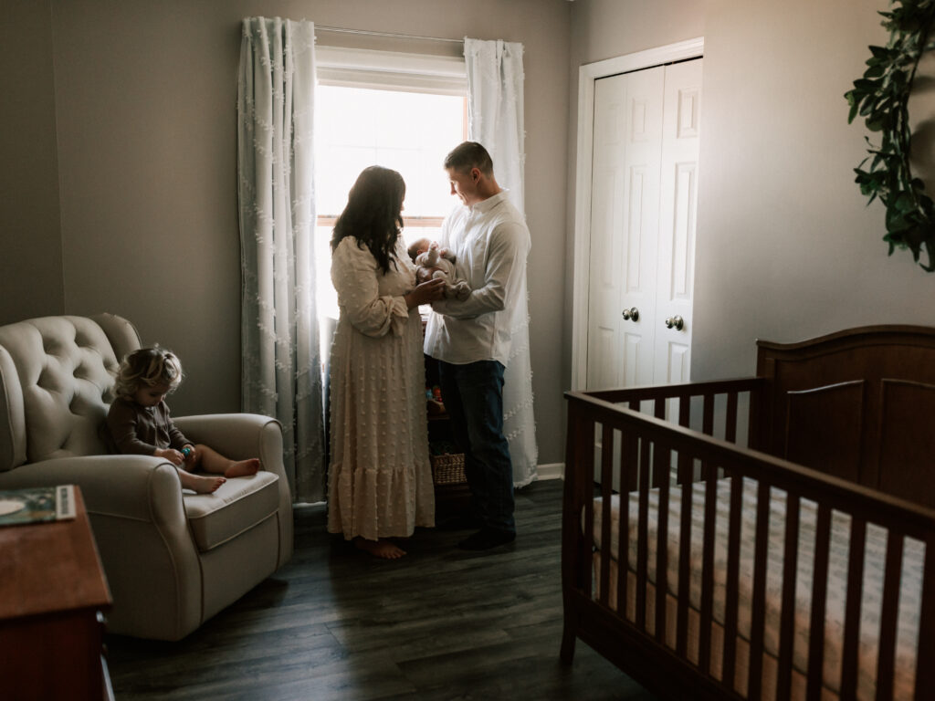 mom and dad holding newborn baby boy in nursery for in home lifestyle photoshoot Canon EOS 5D Mark IV Review