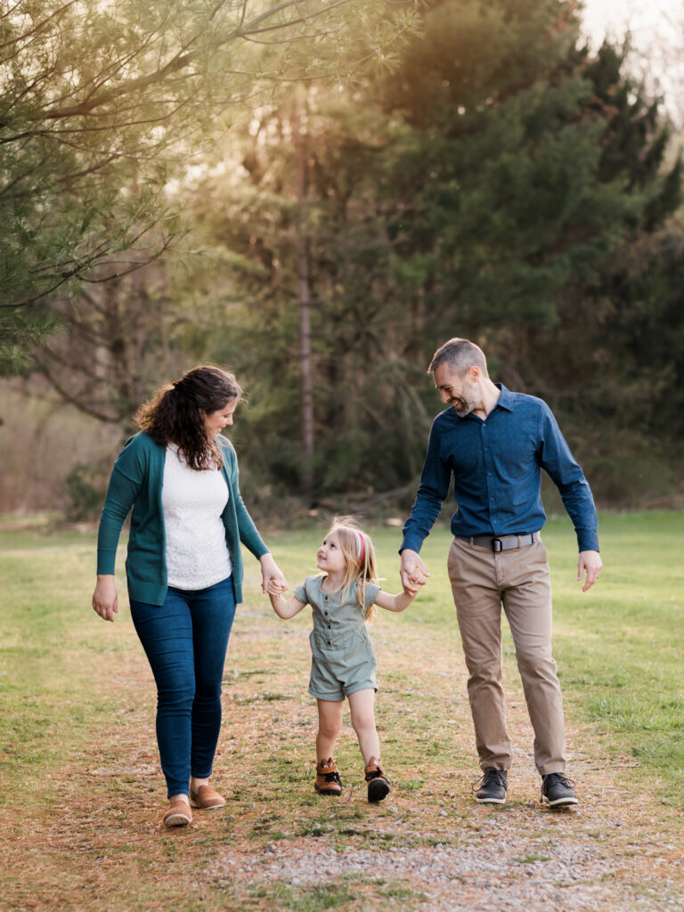 mom and dad holding daughters hand walking through park for family photos Canon EOS 5D Mark IV Review