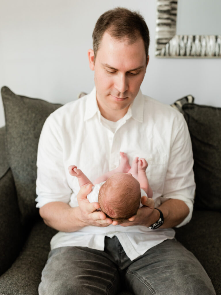 dad holding newborn baby girl in living room