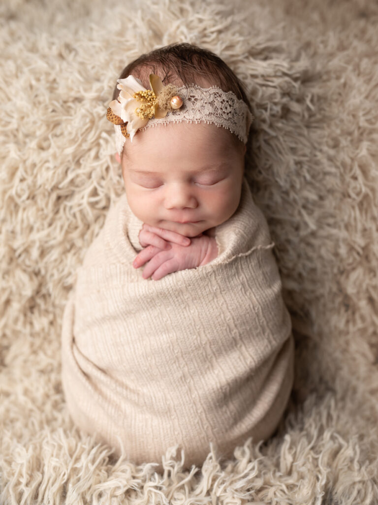 newborn baby wrapped in beige for portraits