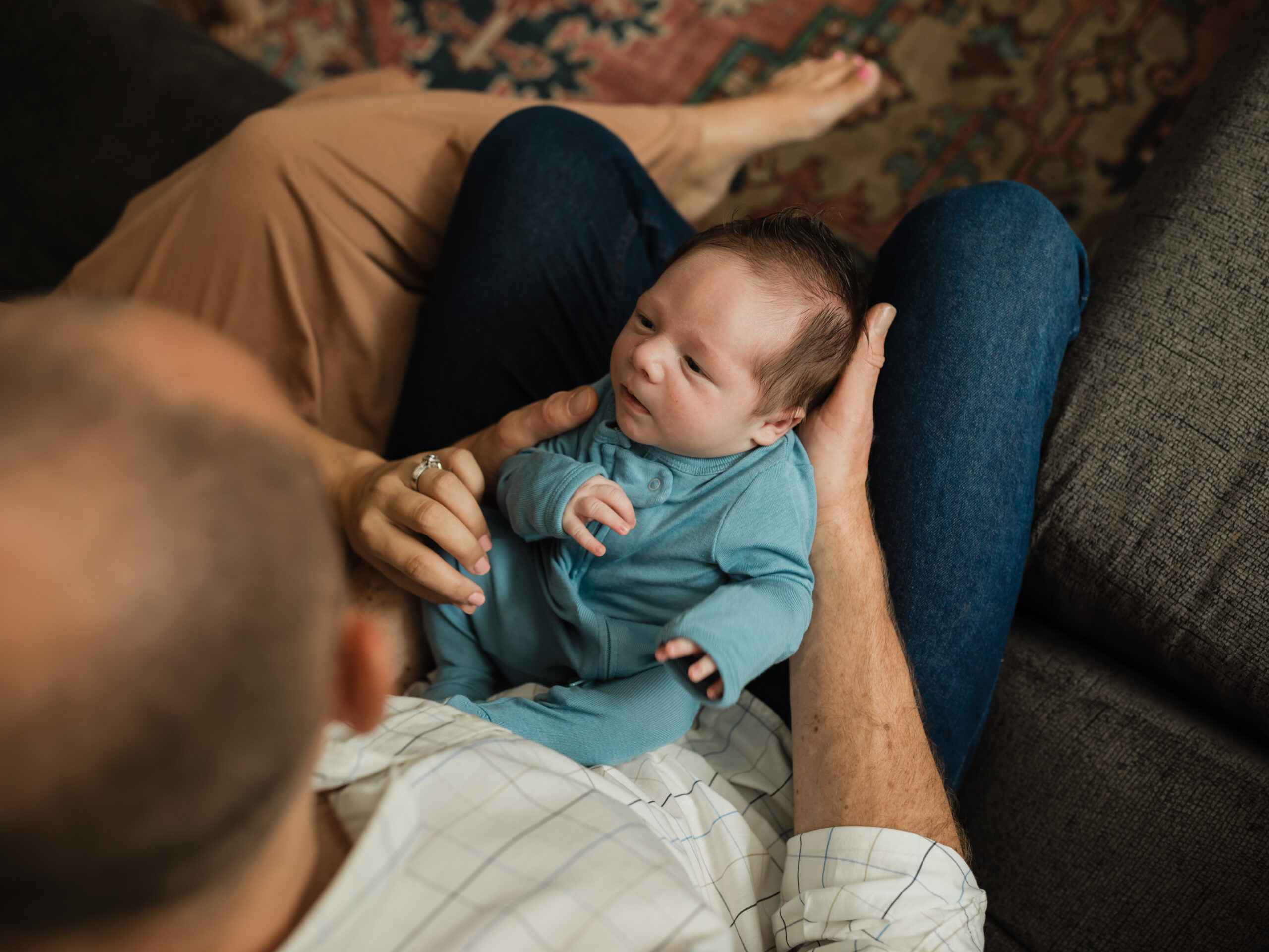 newborn baby boy laying on dad's lap for in home lifestyle session Richfield Chiropractor