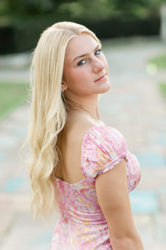 girl in pink dress posing for senior pictures
