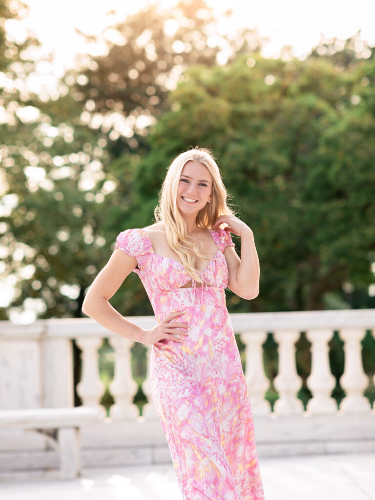 girl in pink dress posing for senior pictures