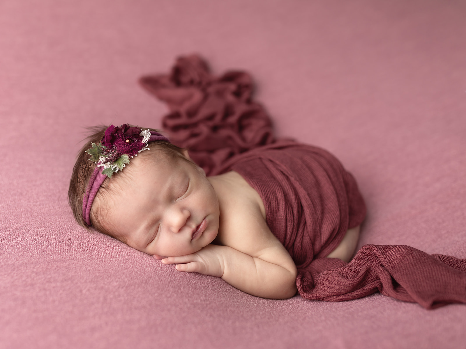 A newborn baby sleeps in froggy pose under a purple blanket Little Bellies Cleveland
