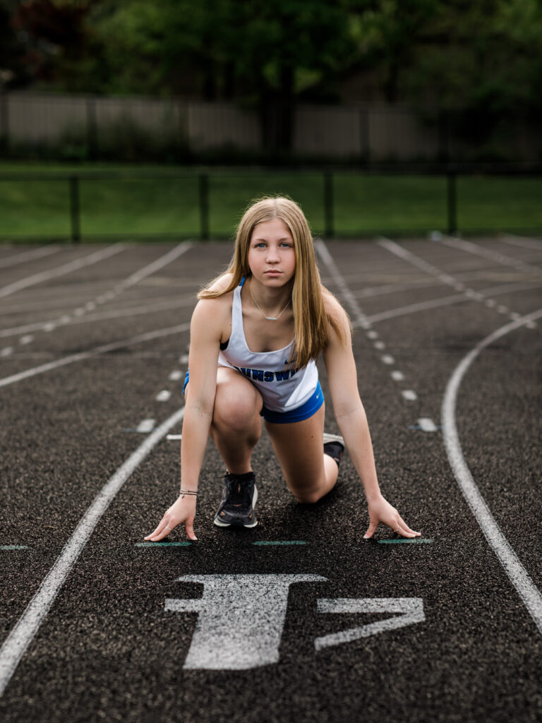 Girl posing on track field for senior portraits
