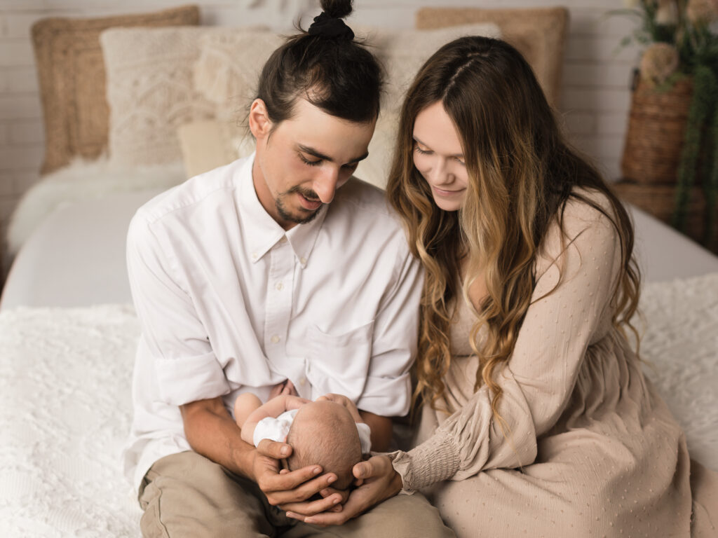 mom and dad hoding newborn baby boy for photoshoot
