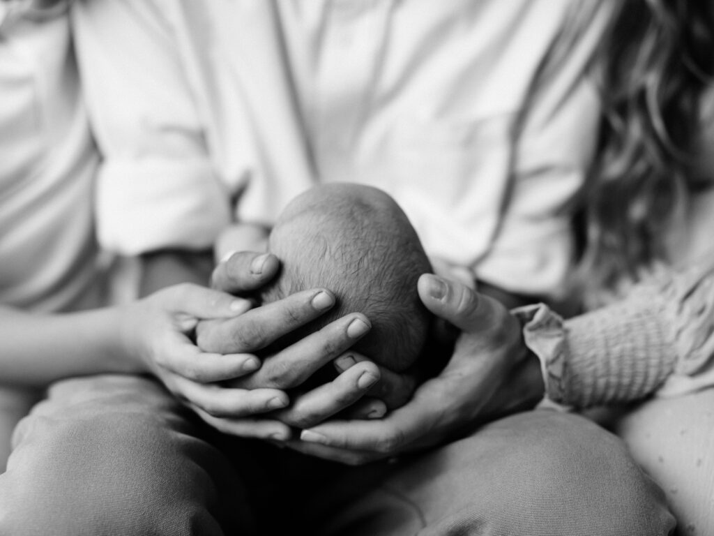 family hands holding newborn baby boy