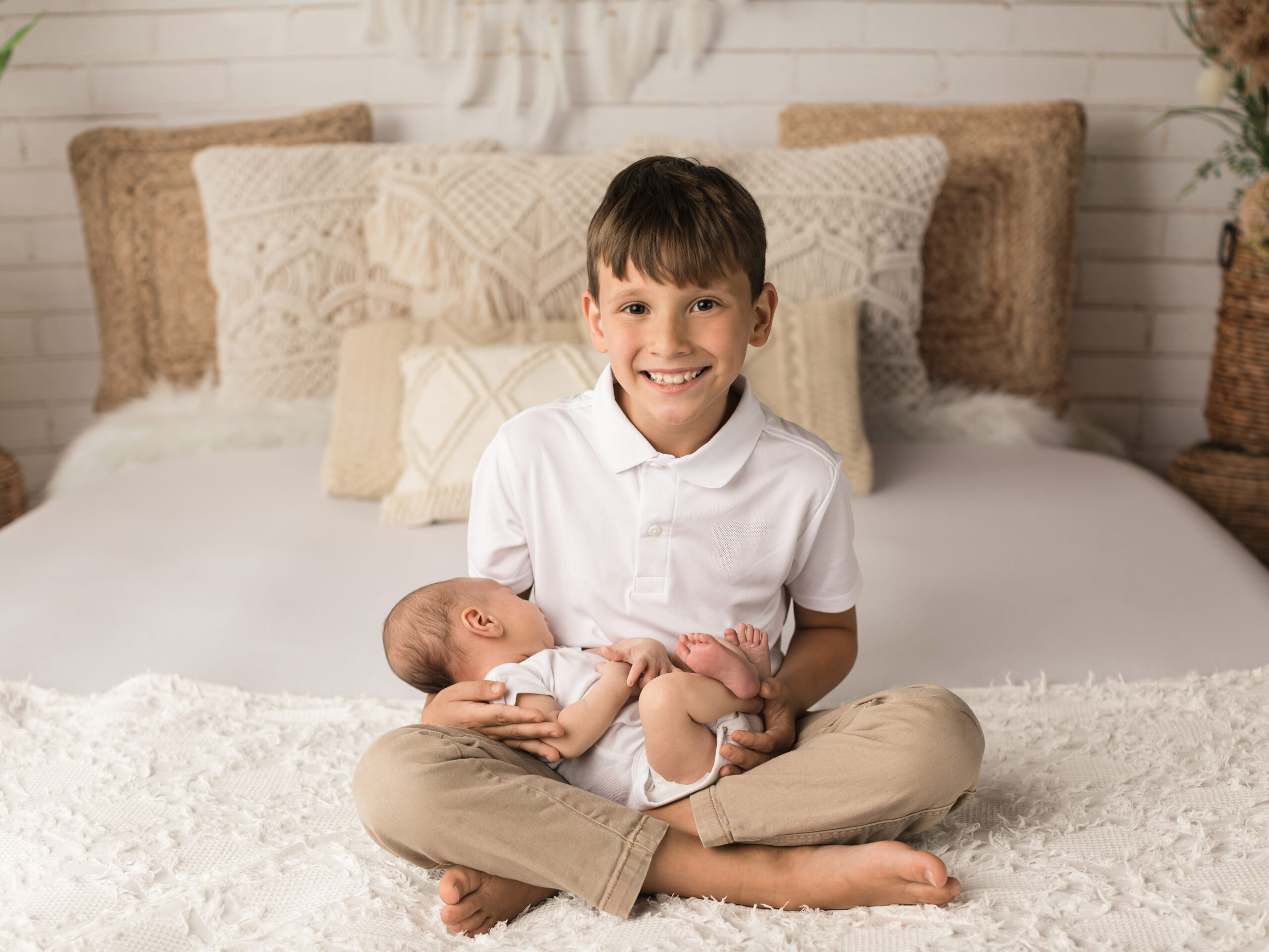 boy holding newborn baby brother for boho newborn photography