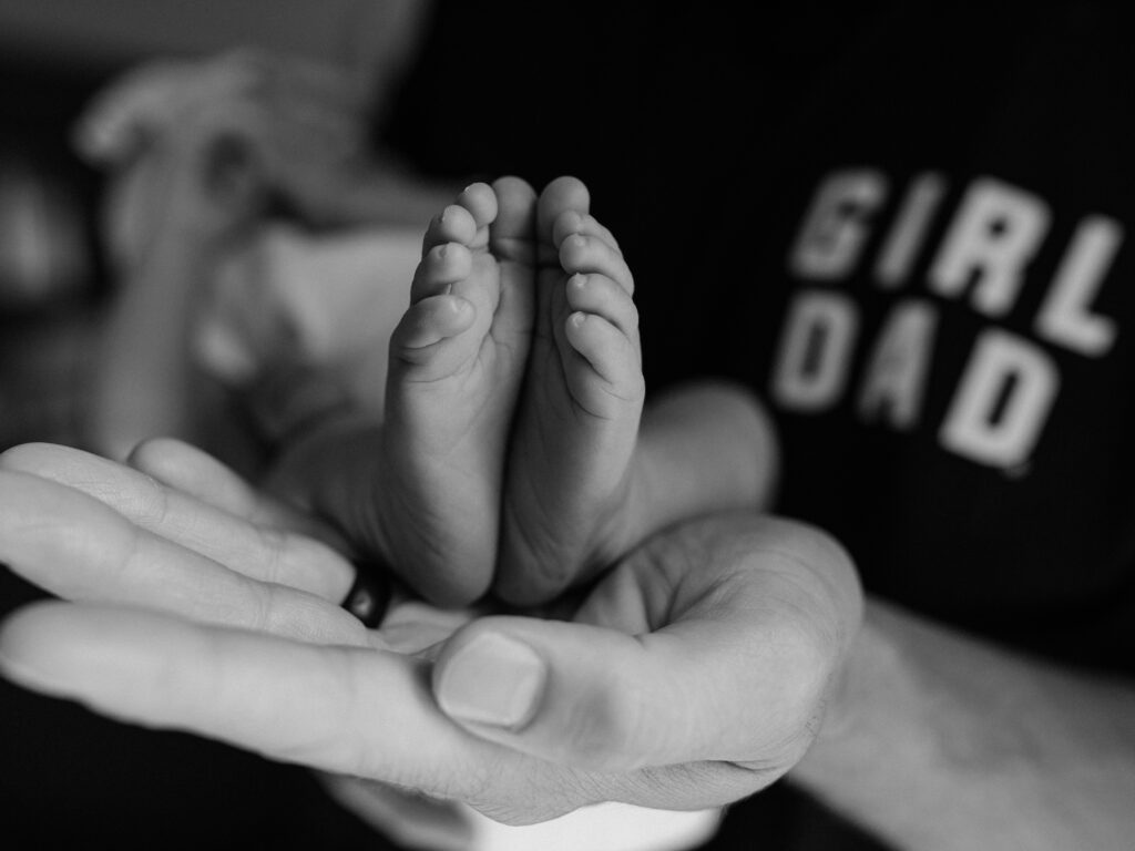 dad holding newborn baby girl showing feet for in home lifestyle newborn photography