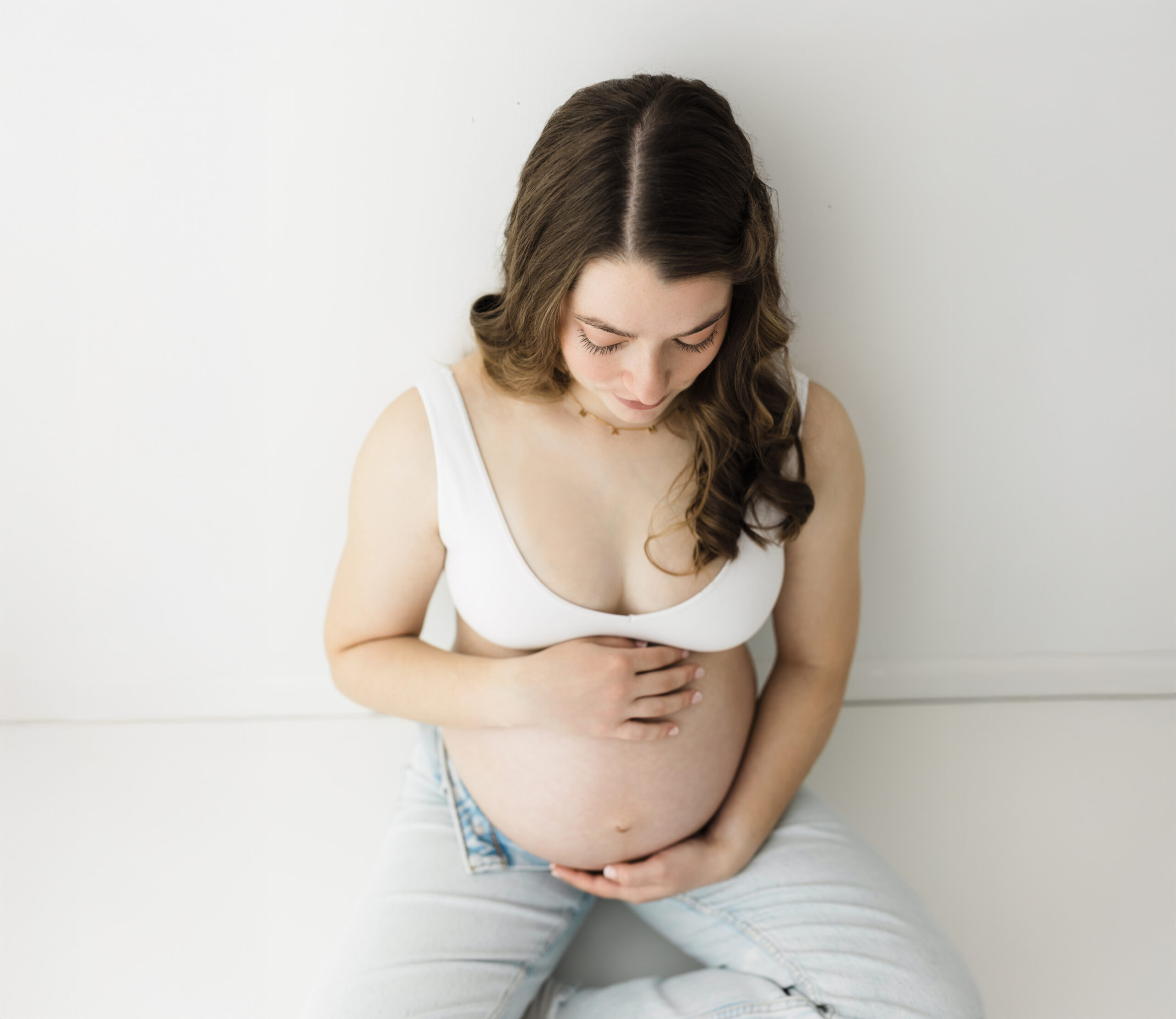 pregnant mom in bra and jeans holding baby bump for maternity photoshoot parenting classes in cleveland