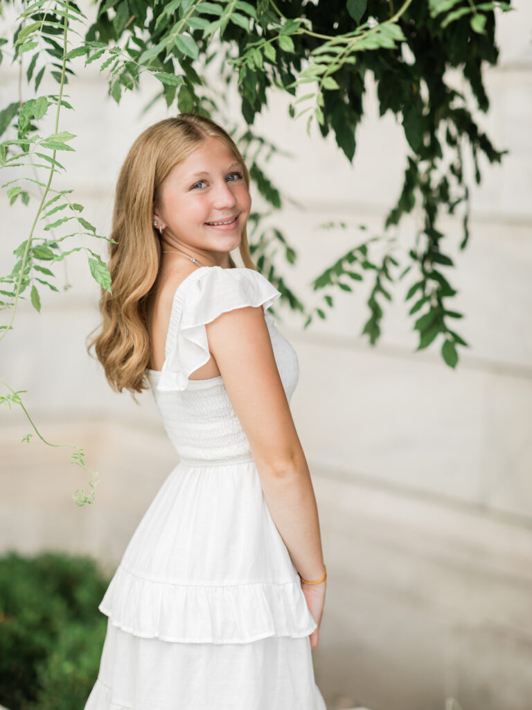 female posing for senior photos in white dress