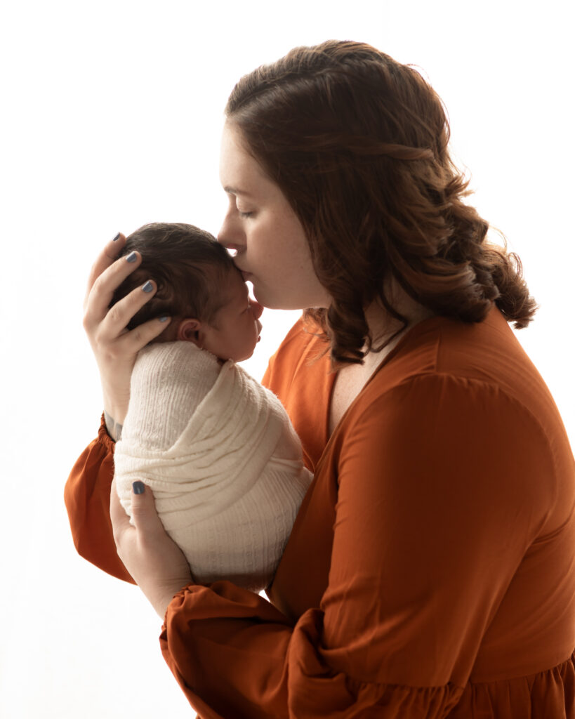 mom kissing newborn baby boy on forehead for newborn studio portraits akron ohio newborn photographer