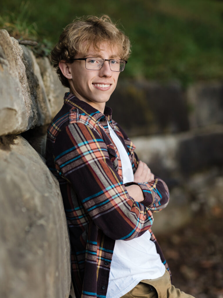 male senior standing against brick wall for portraits