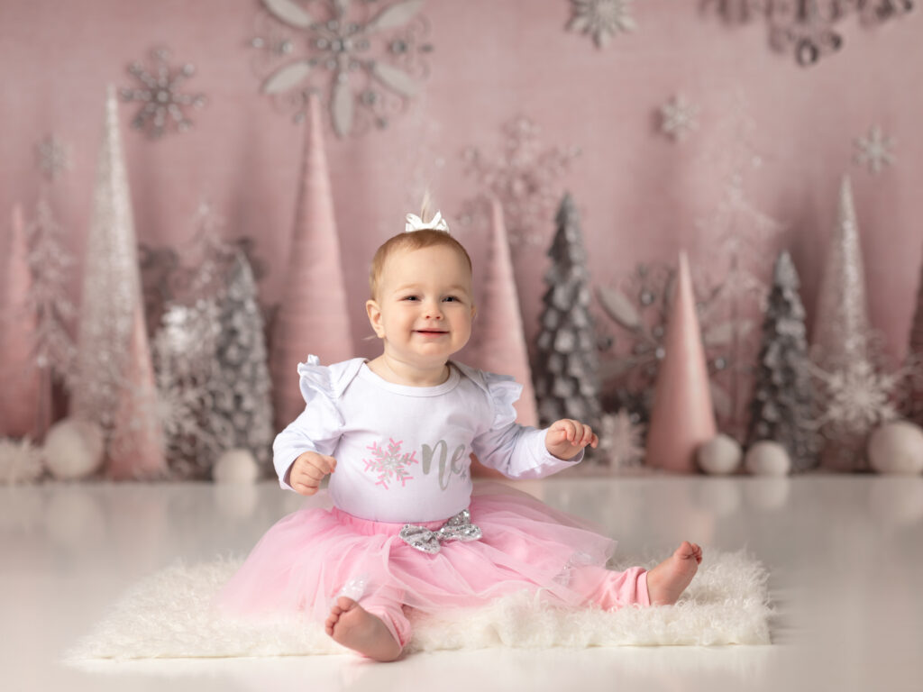 girl in pink tutu smiling for first birthday photos winter onederland birthday theme