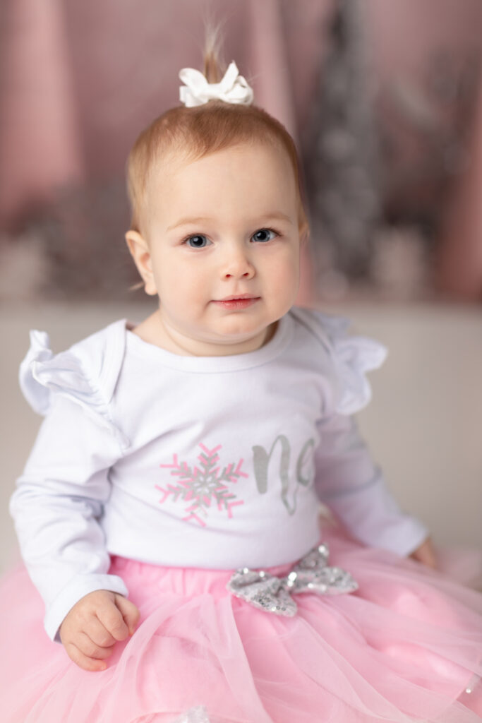 girl in pink tutu smiling for first birthday photos 