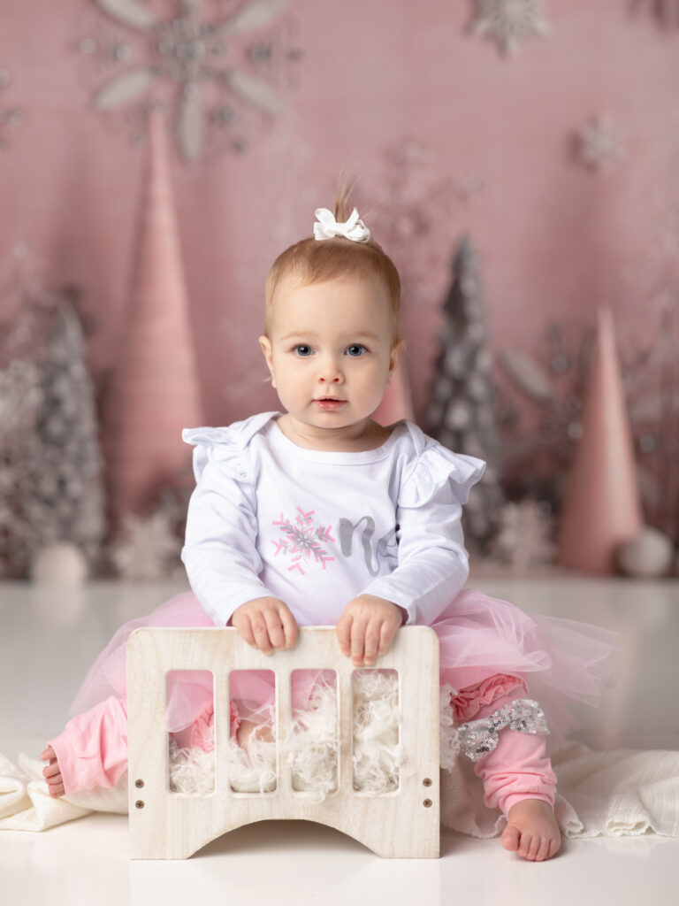 girl in pink tutu smiling for first birthday photos winter onederland birthday theme