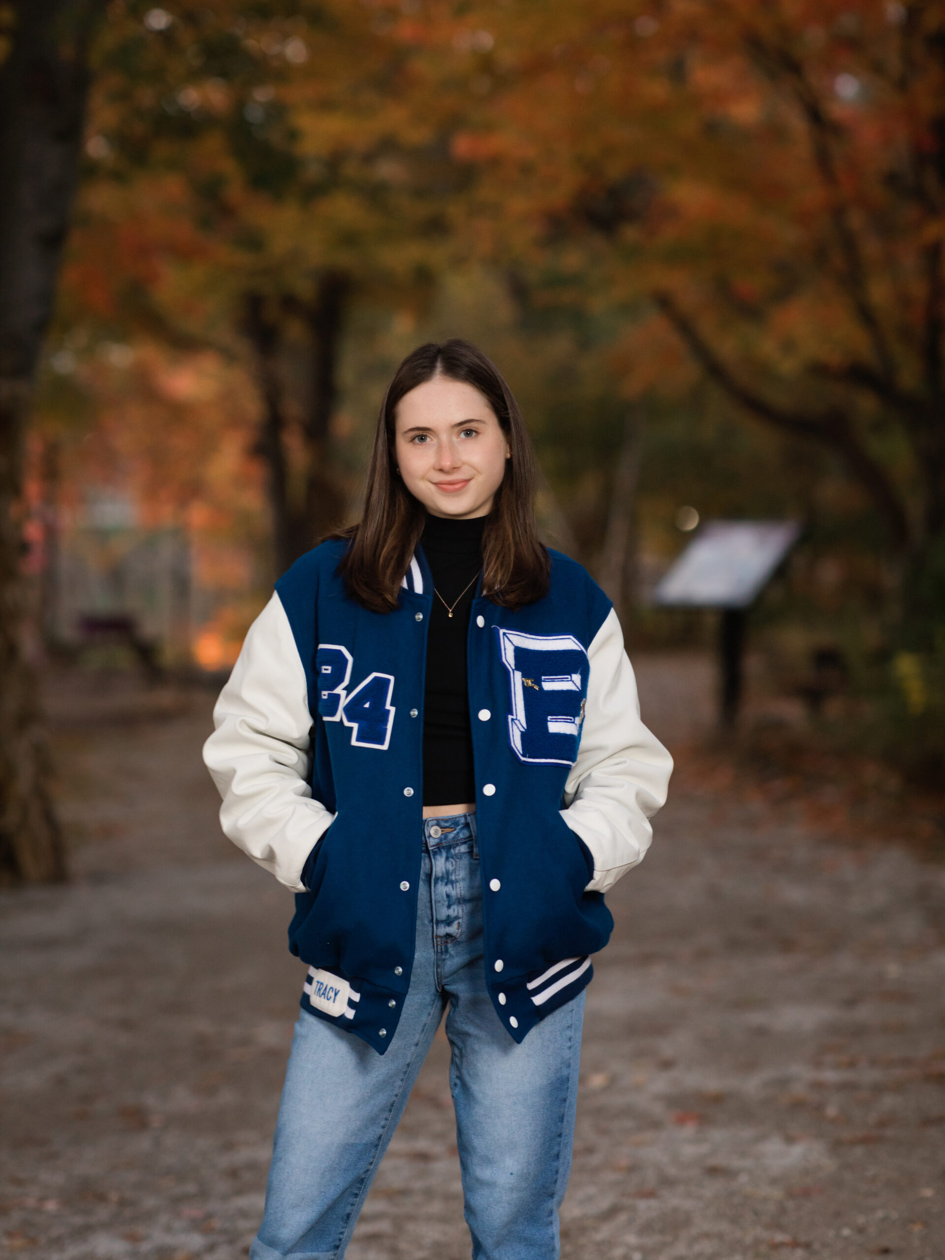 senior girl in letterman jacket posing for senior portraits. Coe Lake Berea Ohio