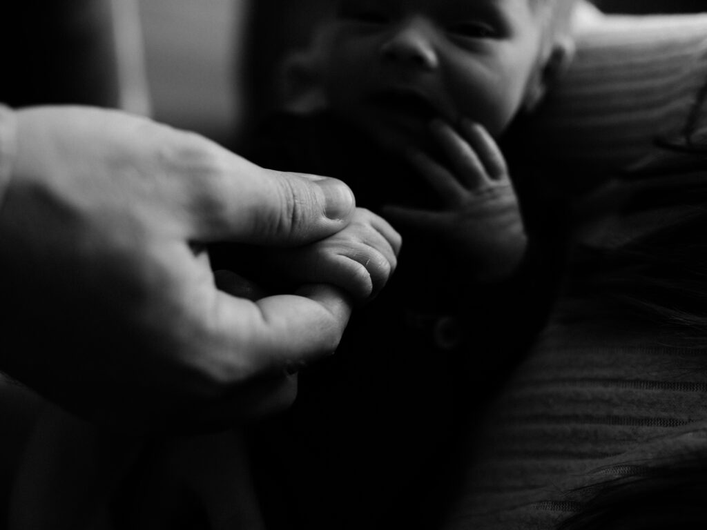 dad holding newborn baby boy hand for in home photoshoot