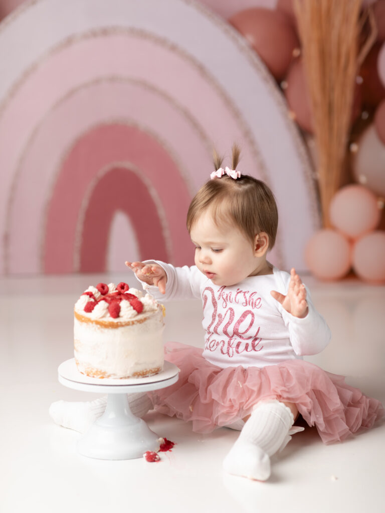one year old girl sitting with cake for cake smash photoshoot akron ohio photographer