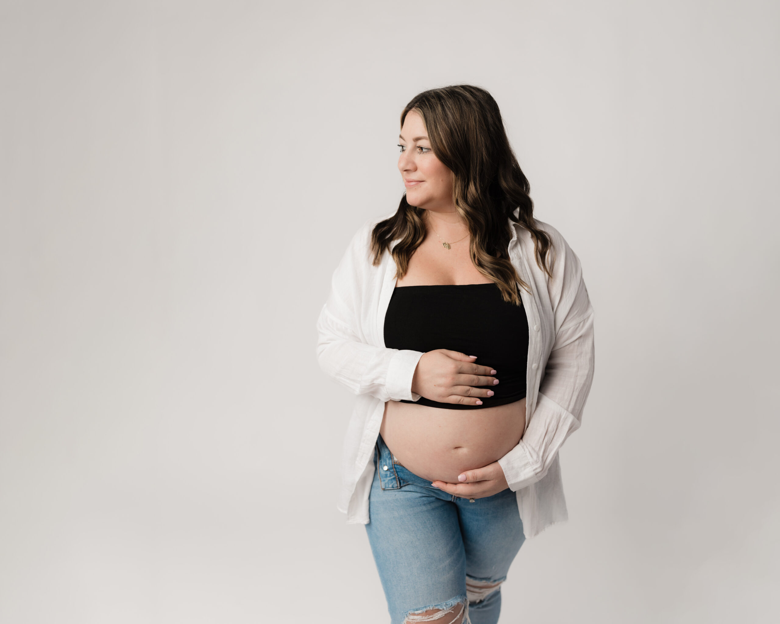 pregnant mom posed holding belly for maternity studio portraits Shaker Womens Wellness