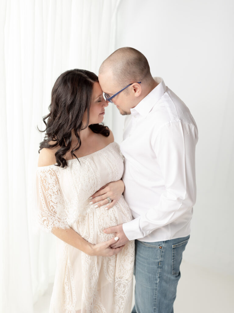 husband and wife holding pregnant belly for maternity photos Shaker Womens Wellness