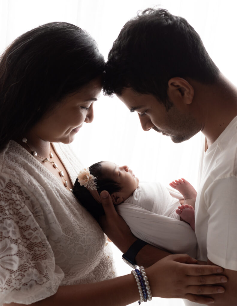 mom and dad holding newborn baby girl wrapped in white baby shower venues Cleveland