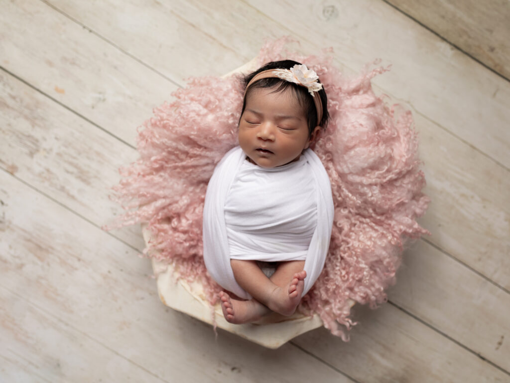 newborn baby girl wrapped in white for studio portraits