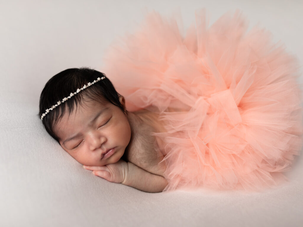 newborn baby girl in pink tutu posed for studio portraits 