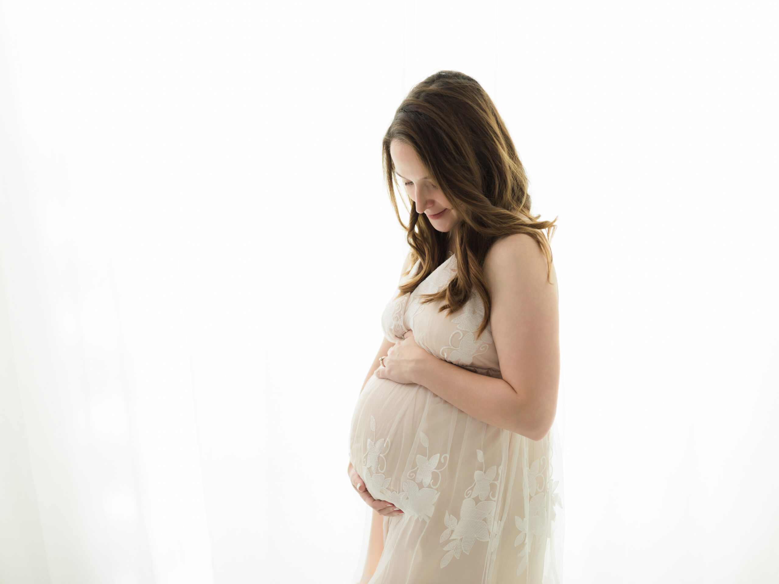 pregnant mother holding baby bump in cream maternity gown summa obgyn akron