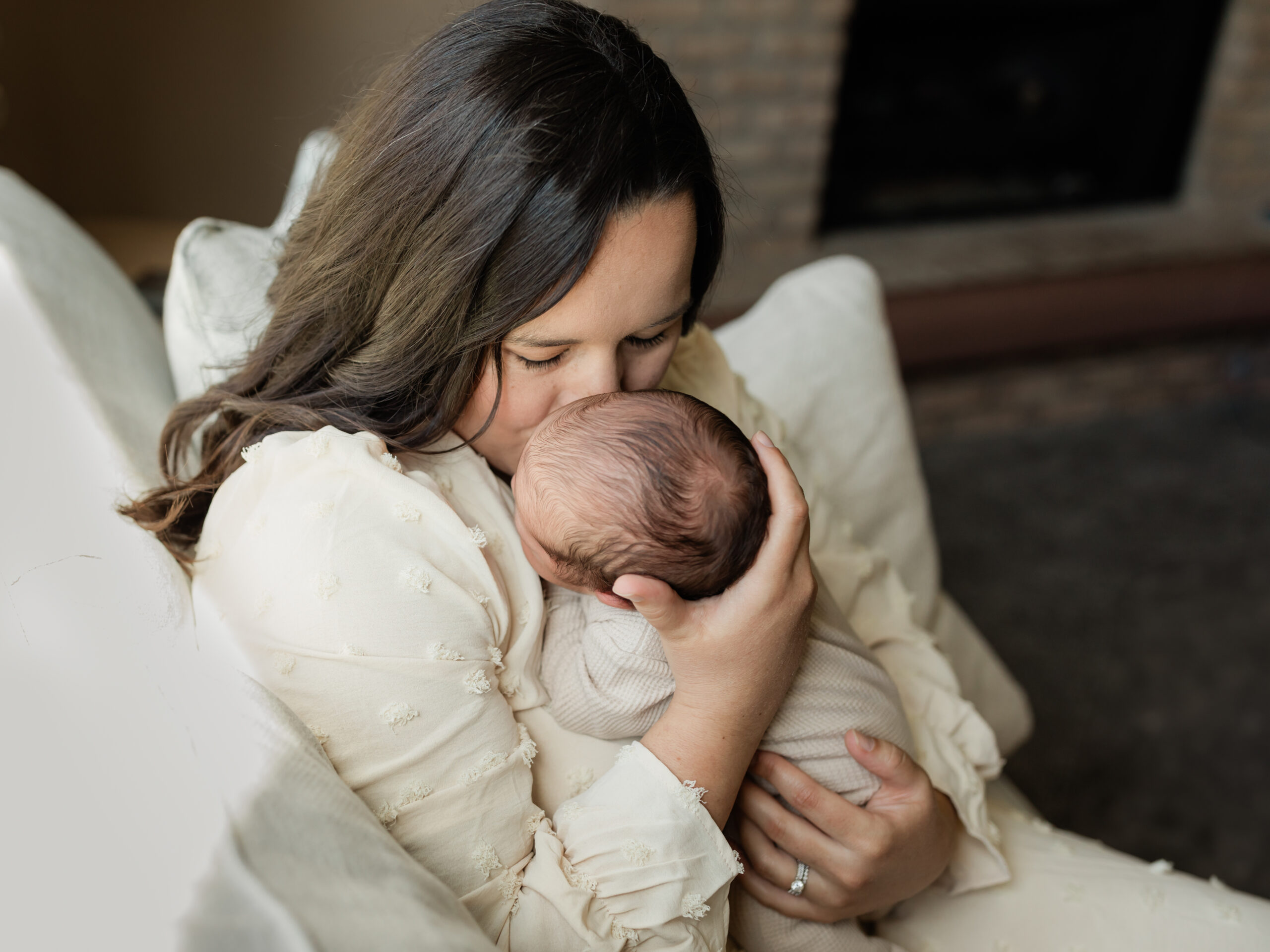 mom kissing newborn baby boy for in home lifestyle photoshoot Hatch Boutique