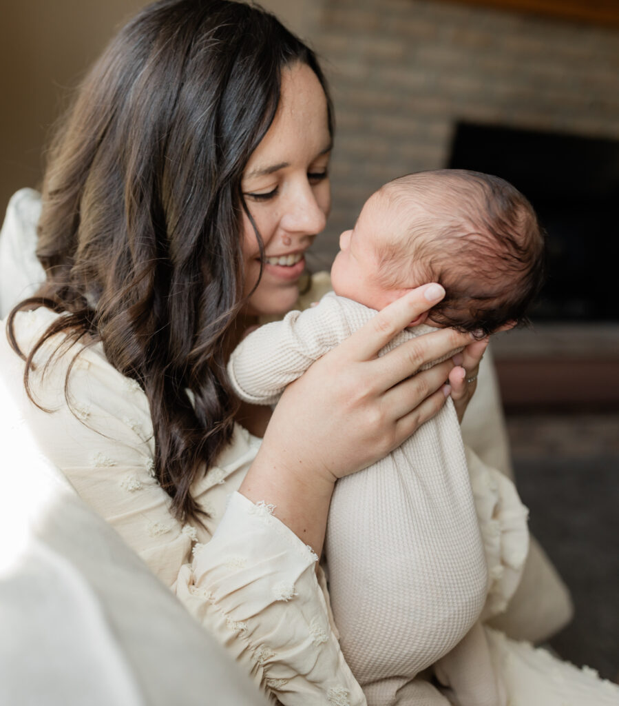 mom holding newborn baby boy on couch for in home newborn session 