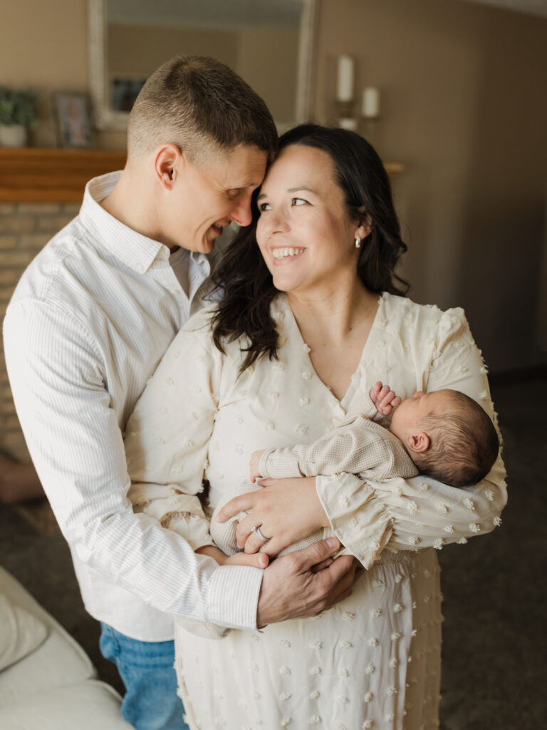 mom and dad holding newborn baby boy in living room for in home lifestyle session 