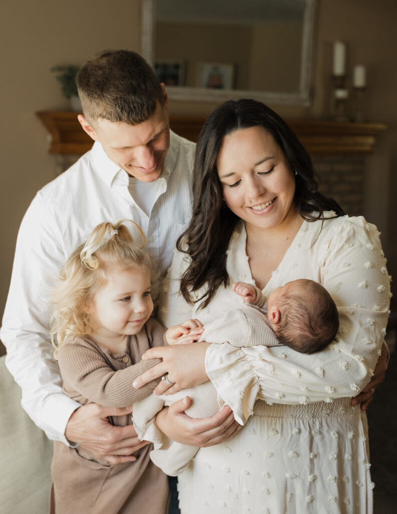 mom, dad and sister holding newborn baby boy in living room for in home lifestyle session 