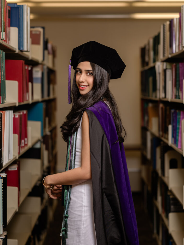 graduate in cap and gown at library 