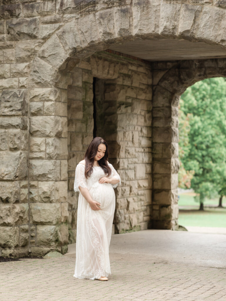 pregnant mother in white lace dress holding belly for maternity photos