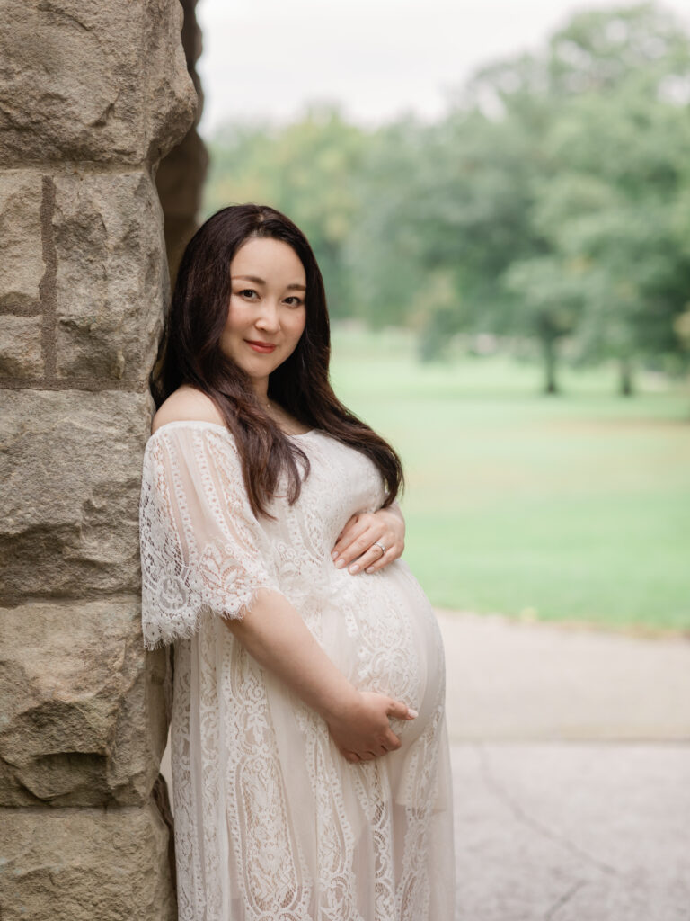 pregnant mother in white lace dress holding belly for maternity photos