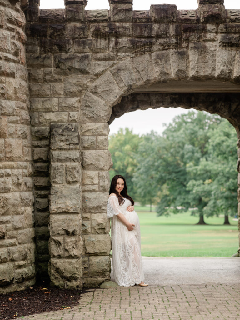 pregnant mother in white lace dress holding belly for maternity photos