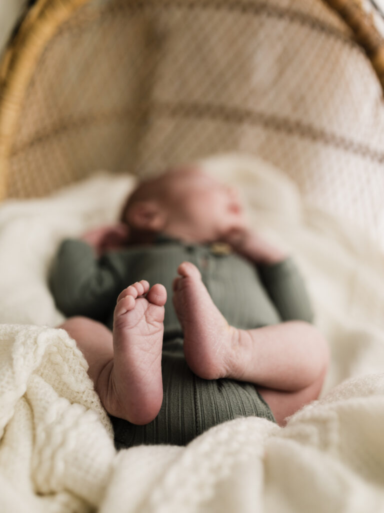newborn baby boy in green onesie laying in bassinet for studio portraits Northeast Ohio Newborn Photographer