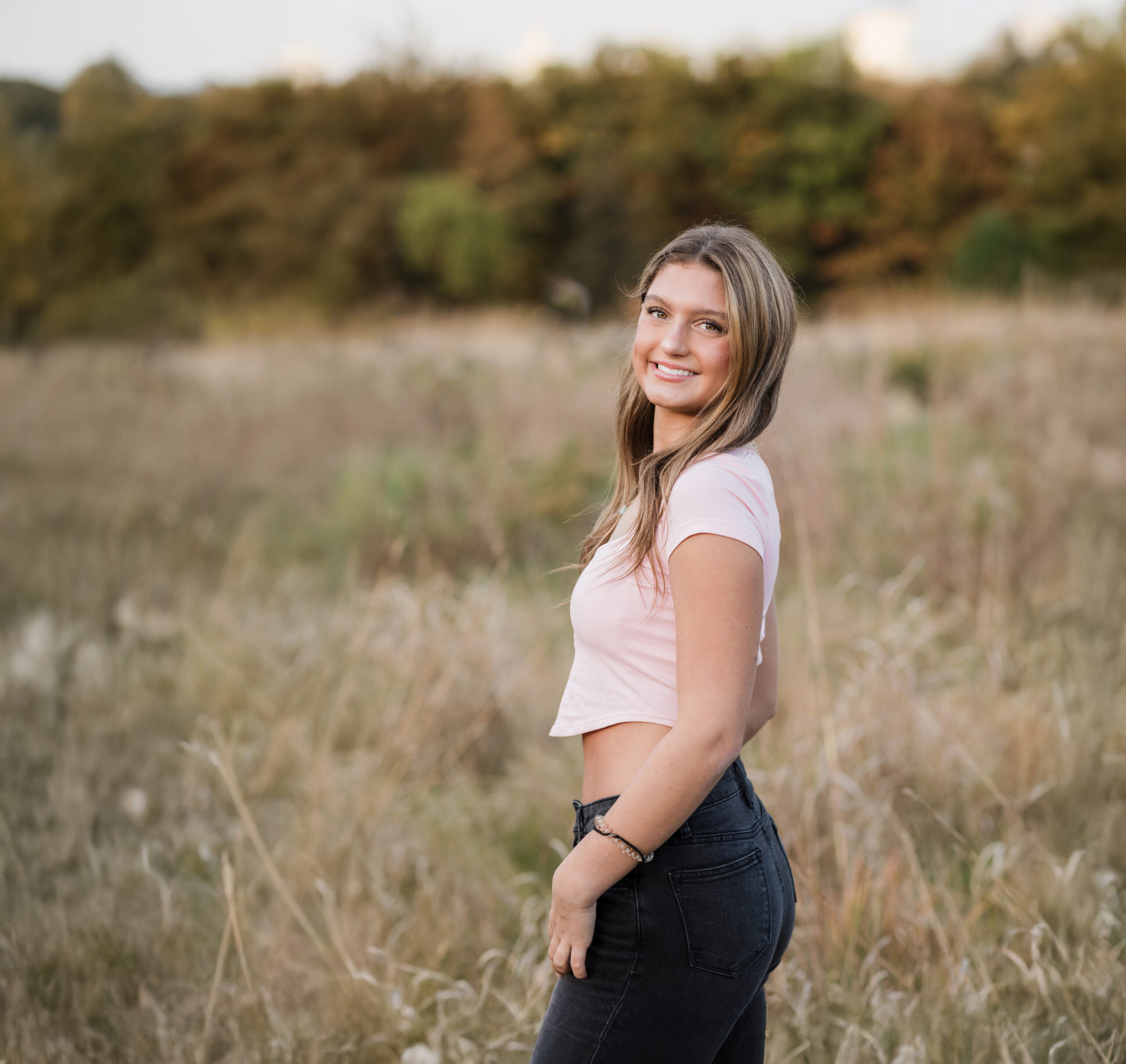 high school senior girl in pink shirt posing in park for senior photography Ohio Senior Photography
